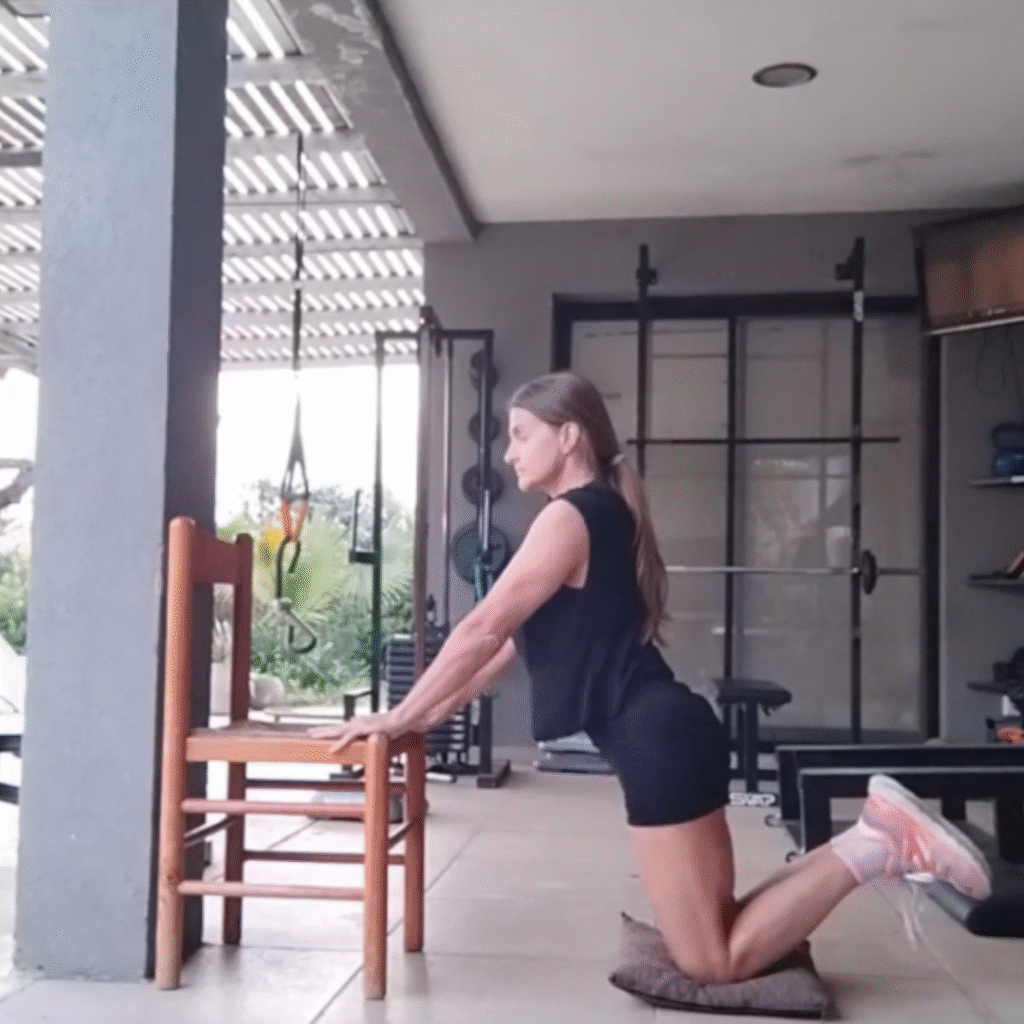 Persona realizando flexiones de brazos apoyada en una silla, paso metodológico 2 para progresar hacia la flexión completa