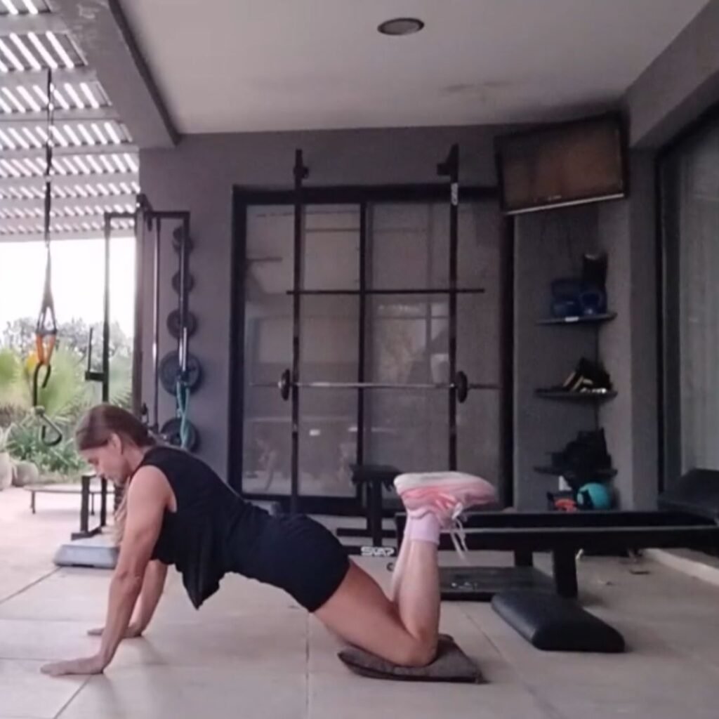 Persona realizando flexiones de brazos apoyadas las rodillas en el suelo paso metodológico 4 para progresar hacia la flexión completa.