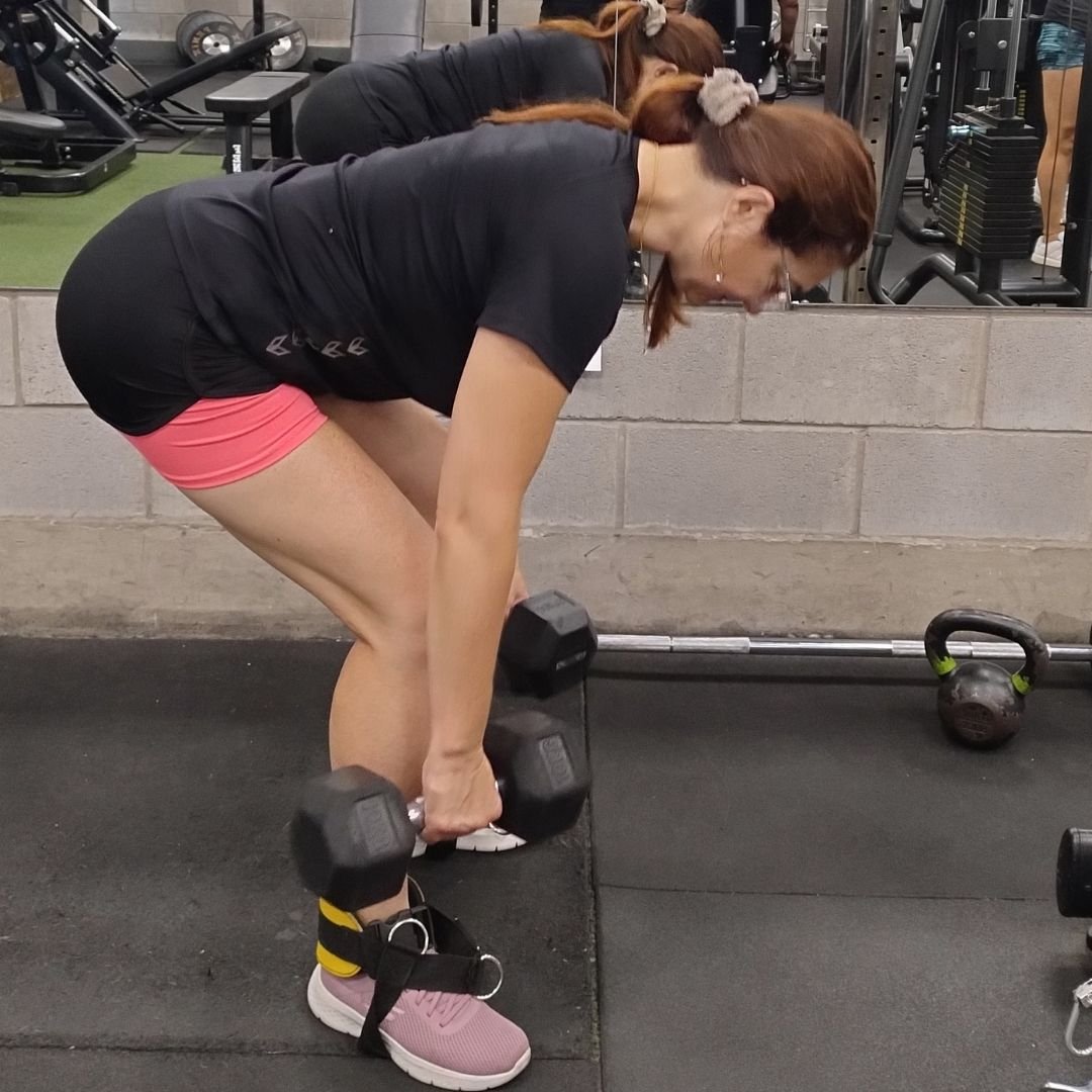 Mujer adulta realizando ejercicio de peso muerto para fortalecer la musculatura posterior dentro de un entrenamiento de fuerza orientado a la salud y la funcionalidad.