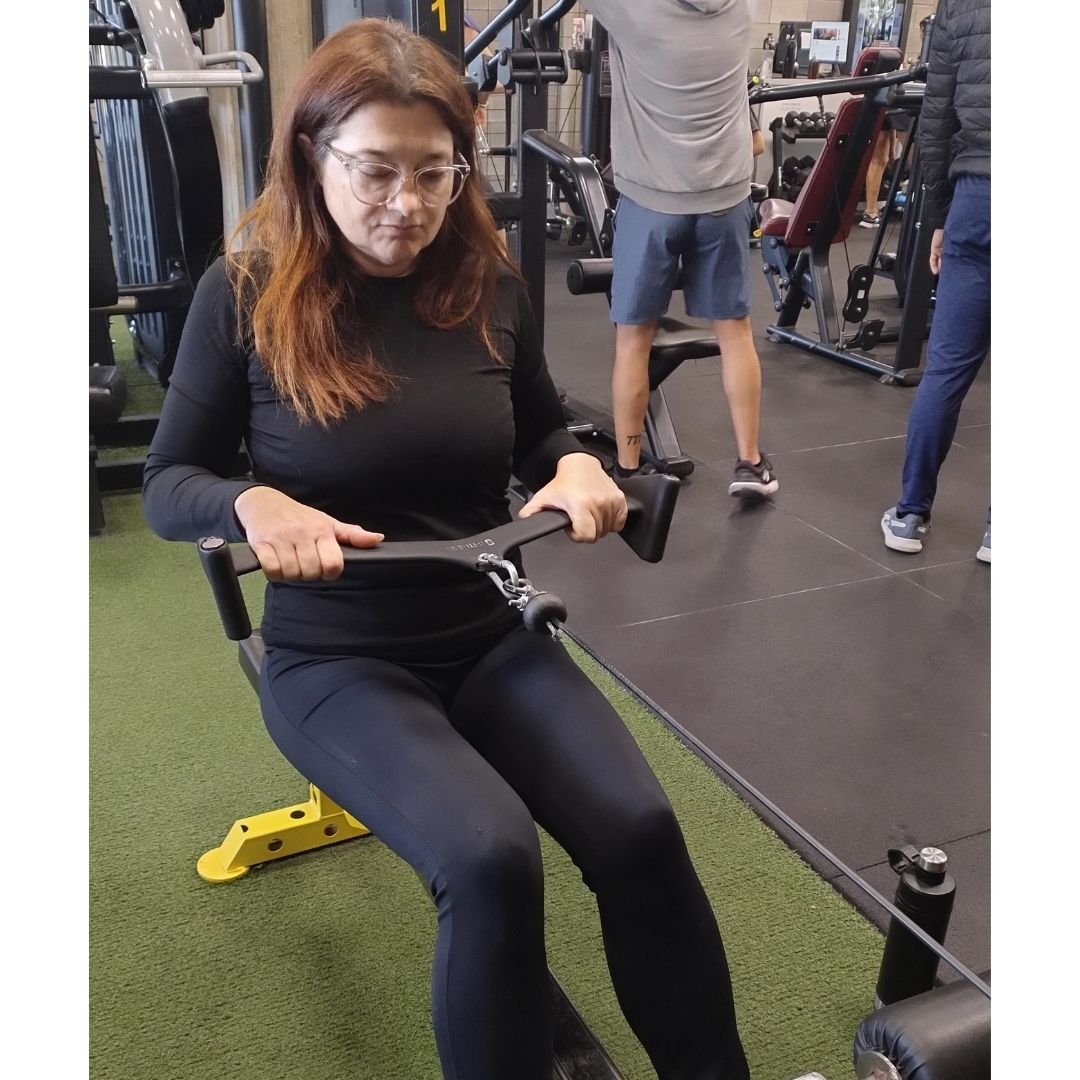 Mujer adulta realizando ejercicio de remo para fortalecer la espalda y los brazos como parte de un entrenamiento de fuerza orientado a la salud y la funcionalidad.